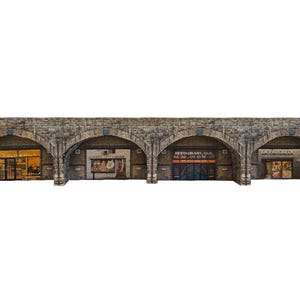 Puede incluir: Un modelo de un edificio de ladrillo con cuatro puertas arqueadas. Las puertas tienen diferentes escaparates con letreros que dicen "Day Provision", "Restaurante, Bar, Cerveza, En el Menú", "Carnicero" y "Panadería".