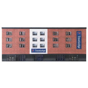 Könnte beinhalten: Ein rotes Backsteingebäude mit einem weißen Schild, auf dem "Travelodge" steht, und einem blauen Schild, auf dem "Travelodge" steht. Das Gebäude hat viele Fenster und ein schwarzes Vordach.