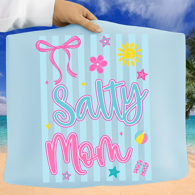 Pu&ograve; includere: Un telo mare azzurro chiaro con strisce verticali e la scritta "Salty Mom" in un carattere giocoso. L'asciugamano presenta grafiche a tema spiaggia rosa e gialle, tra cui un fiocco, stelle, un fiore, un sole, un pallone da spiaggia e infradito.