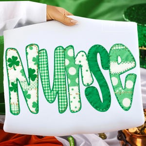 May include: A white cushion displaying the word "NURSE" in green, patchwork letters. The letters feature shamrocks, gingham, and polka dot patterns. The cushion is held by a person.