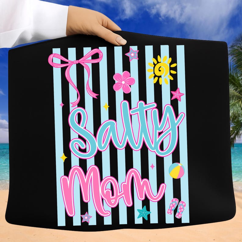 Pu&ograve; includere: Borsa tote nera con un design a tema spiaggia. Il design include le parole "Salty Mom" in rosa e turchese, insieme a un fiocco rosa, stelle, un fiore, un sole, un pallone da spiaggia e infradito. Lo sfondo ha strisce verticali blu.