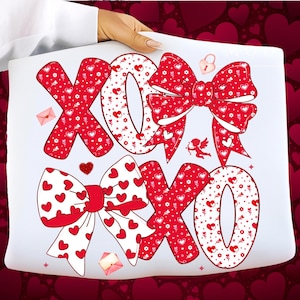 May include: White tote bag with a red and white design featuring the letters "XOXO" and bow illustrations. The letters and bows are decorated with hearts and floral patterns, with small Cupid and envelope graphics.