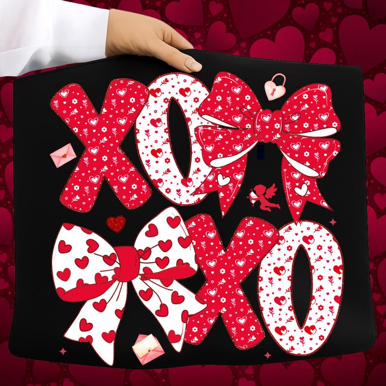 May include: Black tote bag featuring a Valentine's Day design with red bows, hearts, and the letters "XO". The design includes a lock, an angel, and small envelopes.