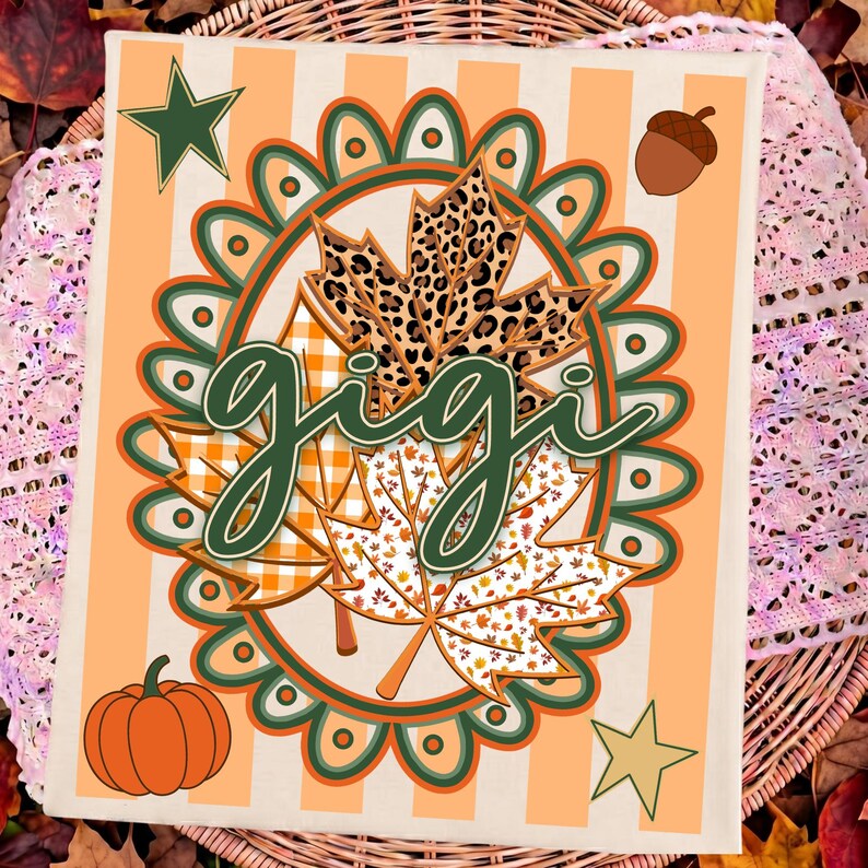 May include: A rectangular sign with a light orange and white striped background featuring the word gigi in dark green script. The design includes a central scalloped oval frame, three maple leaves with leopard, plaid, and leaf patterns, a pumpkin, an acorn, and two stars.