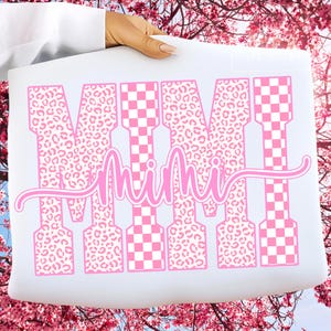 May include: A white sheet with the word "MIMI" in pink. The letters are a mix of leopard print and a pink and white checkerboard pattern. The word "Mimi" is written in a cursive font.