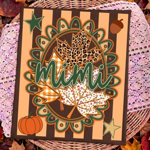 May include: A rectangular sign featuring vertical brown and light orange stripes with a central oval frame containing three maple leaves with leopard print, orange gingham, and white leaf patterns. The word Mimi is written in green script.