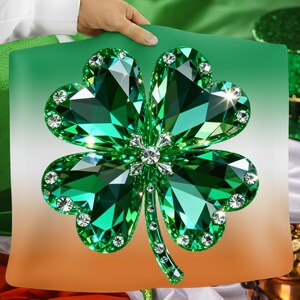 May include: A decorative pillow featuring a large, sparkling green shamrock design. The shamrock is embellished with clear crystals and set against a gradient background of green, white, and orange. The pillow is held by a person.