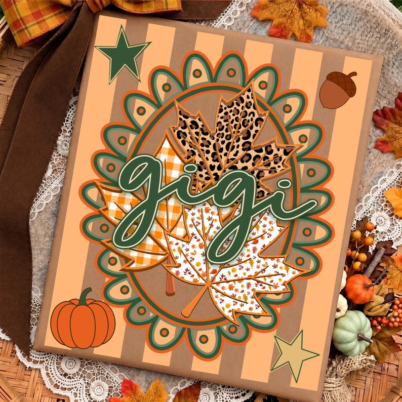 May include: A rectangular sign with a light orange and tan striped background featuring a central scalloped oval frame. Inside the frame are three maple leaves with leopard, orange plaid, and white leaf patterns. The word gigi is written in dark green script.