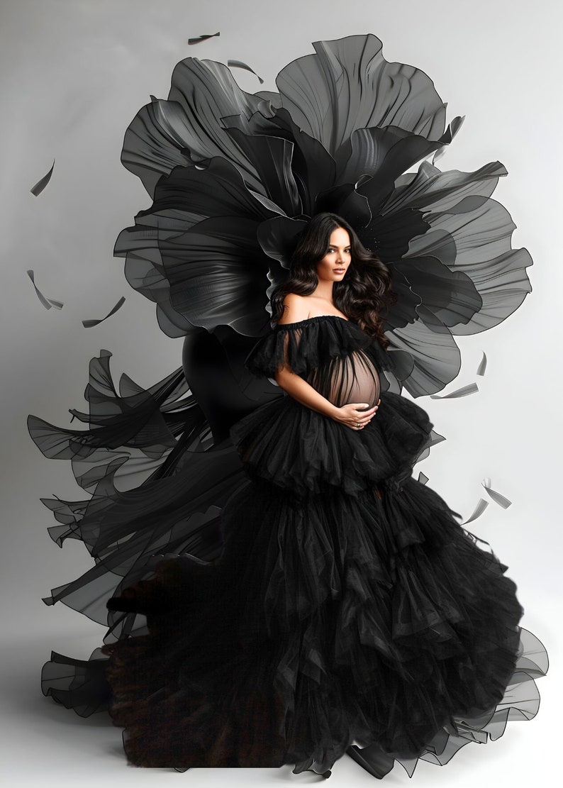 K&ouml;nnte beinhalten: Eine schwangere Person tr&auml;gt ein schwarzes T&uuml;llkleid mit einem gro&szlig;en, schwarzen, blumenf&ouml;rmigen Kopfschmuck. Das Kleid hat mehrere T&uuml;llschichten und der Kopfschmuck ist aus durchsichtigem Stoff.