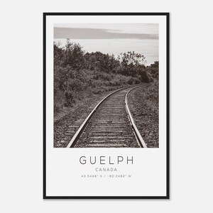 May include: Monochrome photograph of a railway line winding through a natural setting. The image is framed in black and features the text "GUELPH CANADA" and the coordinates 43.5448° N / -80.2482° W.