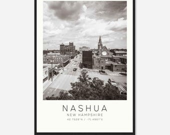 May include: A black and white photograph of Nashua, New Hampshire. The image shows a street lined with buildings, including a church with a tall steeple. The text "Nashua, New Hampshire 42.7528°N -71.4967°E" is printed below the image.