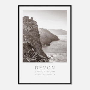 Peut inclure: Tirage encadré en noir et blanc d'un paysage côtier avec des falaises et la mer. Le tirage comprend le texte "DEVON", "UNITED KINGDOM" et des coordonnées. Une personne est visible sur la falaise.