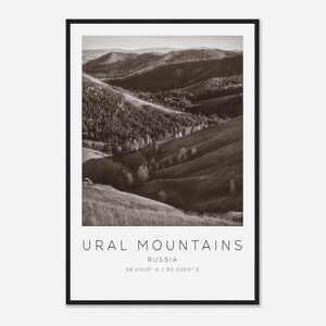 May include: Black and white photograph of the Ural Mountains in Russia. The image shows rolling hills and mountains covered in trees and grass. The text "URAL MOUNTAINS RUSSIA 58.0000° N / 60.0000° E" is printed at the bottom of the image.