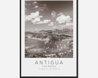 May include: A black and white photograph of a tropical island with a body of water and boats. The text "ANTIGUA CARIBBEAN 17.0608° N / 61.7964° W" is at the bottom of the image.