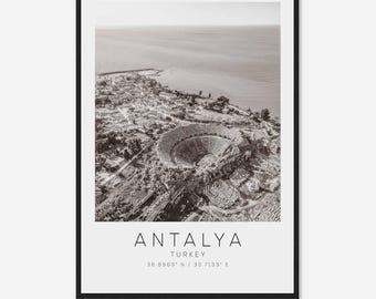 May include: A black and white aerial photograph of Antalya, Turkey. The image shows a large amphitheater-like structure surrounded by buildings and trees. The text "ANTALYA TURKEY 36.8969° N / 30.7133° E" is printed below the image.