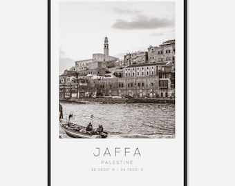 May include: Black and white framed print featuring a coastal cityscape with buildings and a tower. A small boat is in the water. The print includes the text "JAFFA PALESTINE" and coordinates 32.0800° N / 34.7500° E.