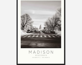 May include: Black and white framed print featuring a street scene in Madison, Wisconsin. The image shows a road with a crosswalk, cars, and bare trees leading to a domed building. The text "MADISON WISCONSIN" is at the bottom.