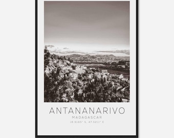 May include: A black and white photograph of Antananarivo, Madagascar. The city is nestled in a valley and surrounded by hills. The text "Antananarivo, Madagascar 18.9185° S, 47.5211° E" is printed below the image.