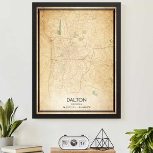 Puede incluir: Una impresión de mapa de estilo vintage de Dalton, Georgia, con un marco negro. El mapa muestra las calles y los puntos de referencia de la ciudad. El texto "DALTON GEORGIA 34.7601°N / -84.9480°E" está impreso en la parte inferior del mapa.