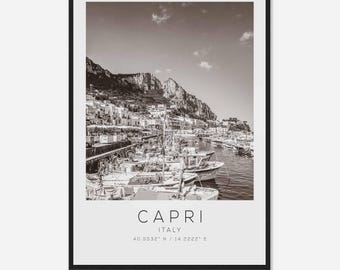 May include: A black and white photograph of a harbor in Capri, Italy. The photo shows a row of boats docked at the harbor, with the town of Capri in the background. The text "CAPRI ITALY 40.5532° N / 14.2222° E" is printed at the bottom of the photo.