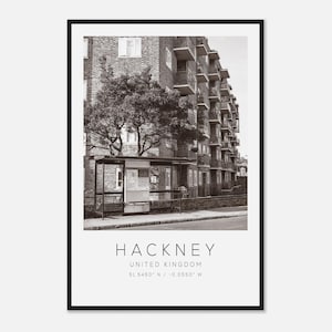 May include: Black and white photograph of a building in Hackney, United Kingdom. The image features a bus stop in front of a brick apartment building. The word "HACKNEY" is printed at the bottom, along with the location and coordinates.