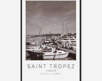 May include: Black and white framed print of Saint Tropez, France. The image features a harbor filled with boats and yachts, with buildings in the background. The text "SAINT TROPEZ FRANCE 43.2711° N / 6.6400° E" is printed at the bottom.