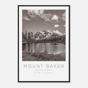 May include: Monochrome framed print featuring Mount Baker in the United States. The image shows a mountain range with snow-capped peaks reflected in a calm lake. The sky is filled with clouds. The text "MOUNT BAKER" and coordinates are at the bottom.