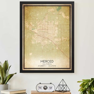 May include: A vintage-style map print of Merced, California. The map is in shades of green and brown and features a black frame. The text "MERCED, CALIFORNIA, 37.2988°N / -120.4714°E" is printed at the bottom of the map.