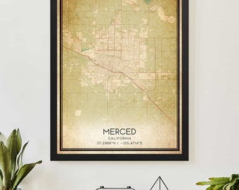 May include: A vintage-style map print of Merced, California. The map is in shades of green and brown and features a black frame. The text "MERCED, CALIFORNIA, 37.2988°N / -120.4714°E" is printed at the bottom of the map.