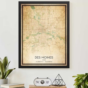 May include: A vintage-style map print of Des Moines, Iowa, with a black frame. The map is beige with green accents and includes the city's name and coordinates: 41.5667° N / -93.6065° E.