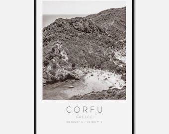 May include: Black and white framed print of Corfu, Greece. The image shows a coastal landscape with a beach, sea, and lush, mountainous terrain. The word "CORFU" is printed in a clean font, along with the country name and coordinates.