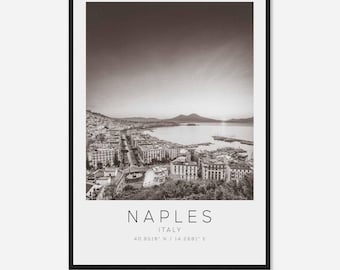 May include: A black and white photograph of Naples, Italy. The photo shows a cityscape with buildings, a bay, and a mountain in the distance. The text "NAPLES ITALY 40.8518° N / 14.2681° E" is printed below the image.
