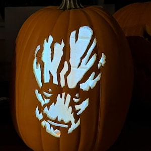 May include: A carved orange pumpkin with a glowing face design. The face is illuminated from within, creating a spooky effect. The pumpkin is a classic Halloween decoration.