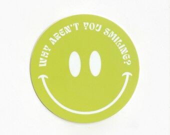 Może przedstawiać: Zielona okrągła naklejka z uśmiechniętą buźką w kolorze białym i tekstem "Why aren't you smiling?" w retro czcionce.