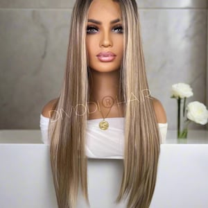 May include: Long, straight, light brown human hair wig with blonde highlights. The wig is styled with a center part and falls to the shoulders.