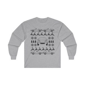 May include: A grey long-sleeved sweatshirt with a festive design. The design features black line art of cars, reindeer, snowflakes, and Christmas trees. The cars are convertibles, and the overall theme is a holiday car-themed design.