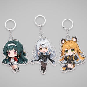 May include: Three anime-style keychains featuring chibi characters. The keychains have silver metal rings and chains. The characters have different hair colors and outfits. One has green hair, one has silver hair, and the last has orange hair.