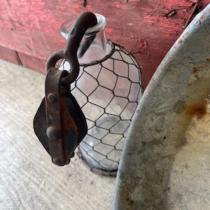 May include: A white ceramic mug with a black handle and the text "But First, Coffee" in a black, bold font. The mug is sitting on a wooden surface. The mug is approximately 4 inches tall.