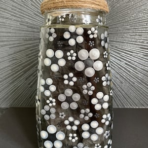 May include: A clear glass vase with brown twine tied around the top. The vase is decorated with white and black polka dots.