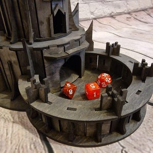 May include: A wooden tower with a circular platform on top. The platform has three red dice with white numbers on them. The dice show the numbers 5, 1, and 20.