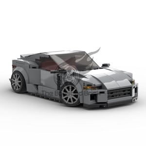 May include: A gray toy car with a sleek, modern design. The car features a low profile, detailed wheels, and a tinted windshield. The vehicle is set against a white background, highlighting its form and structure. The car is a model of a sports car.