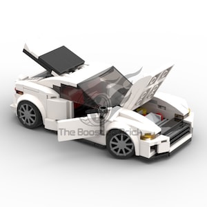May include: A white toy sports car with the hood and doors open, revealing the engine and interior. The car has gray wheels and black accents. The text "The Boost Brick" is visible on the side of the car.