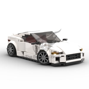 May include: A white toy sports car constructed from interlocking plastic bricks. The car features a sleek design with dark gray wheels, a tinted windshield, and a spoiler. The text "The Bricked Brick" is visible on the side of the car.