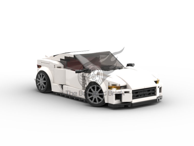 May include: A white toy sports car constructed from interlocking plastic bricks. The car features a sleek design with dark gray wheels, a tinted windshield, and a spoiler. The text "The Bricked Brick" is visible on the side of the car.