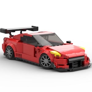 May include: A red Lego model car with a black spoiler and yellow headlights. The car has a detailed interior and a realistic design.