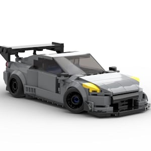 May include: A gray Lego model of a race car with a large rear wing, yellow headlights, and black accents.