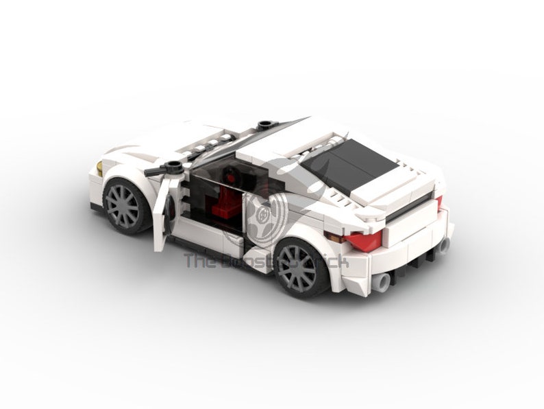 May include: A white toy sports car made of interlocking plastic bricks. The car has a sleek design with a black roof, red interior, and gray wheels. The driver's side door is open, revealing the interior. The car has a rear spoiler and dual exhaust pipes.