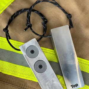 May include: Two silver metal bars with black text. The bar on the left has two round gray circles. The bar on the right has the word "Top" printed on it. The bar on the left has the word "Bottom" printed on it. The bars are attached to a black cord with white dots.