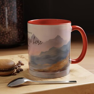 May include: A red and white ceramic mug with a mountain landscape design and the text "My favourite place is here". The mug has a red rim and handle.