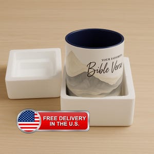 Może przedstawiać: Biały ceramiczny kubek z niebieskim rantem i akwarelowym wzorem gór. Kubek ma nadrukowany tekst "Twój ulubiony werset biblijny". Kubek znajduje się w białym pudełku styropianowym.